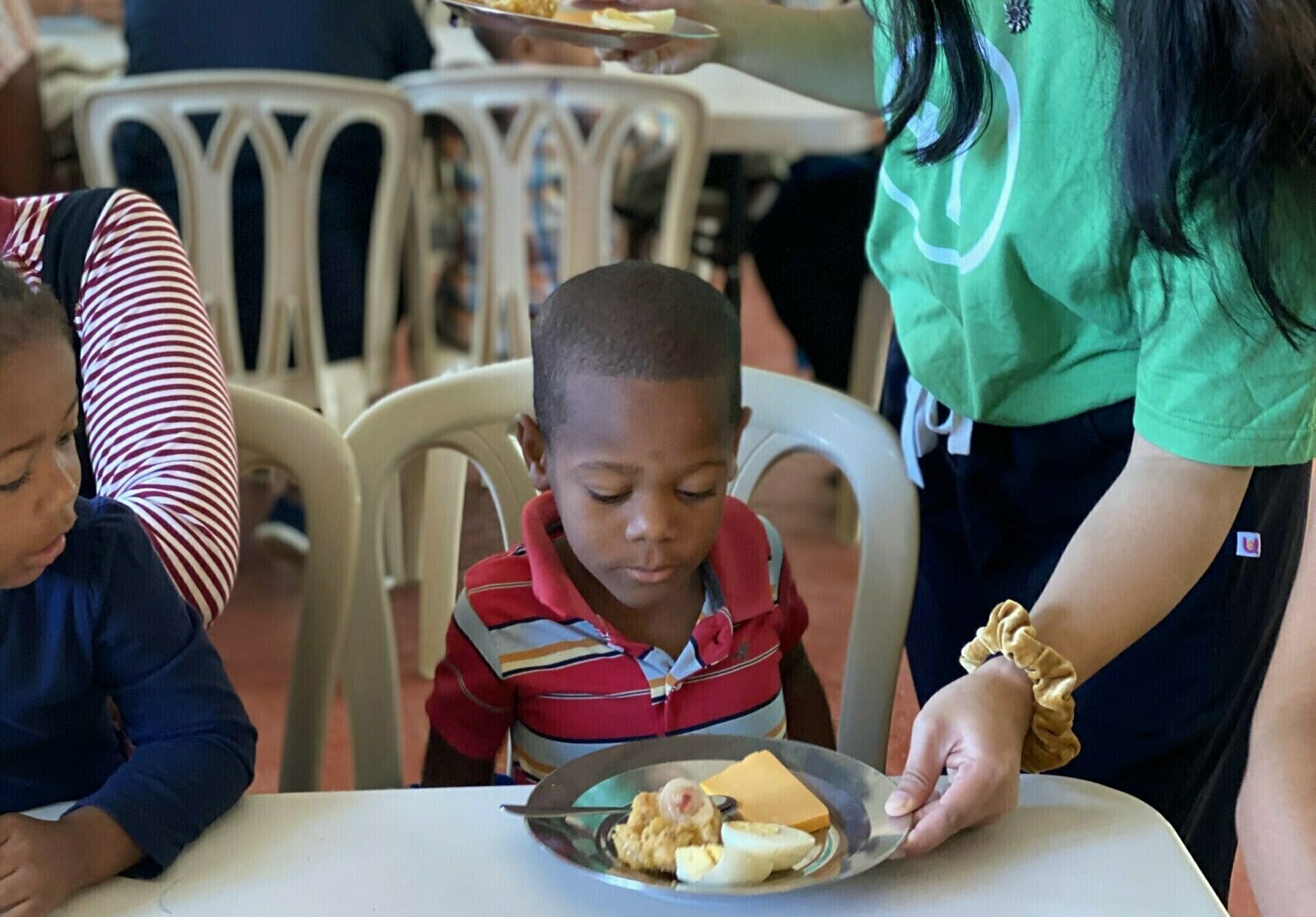 mission trip participants serving a vulnerable child food