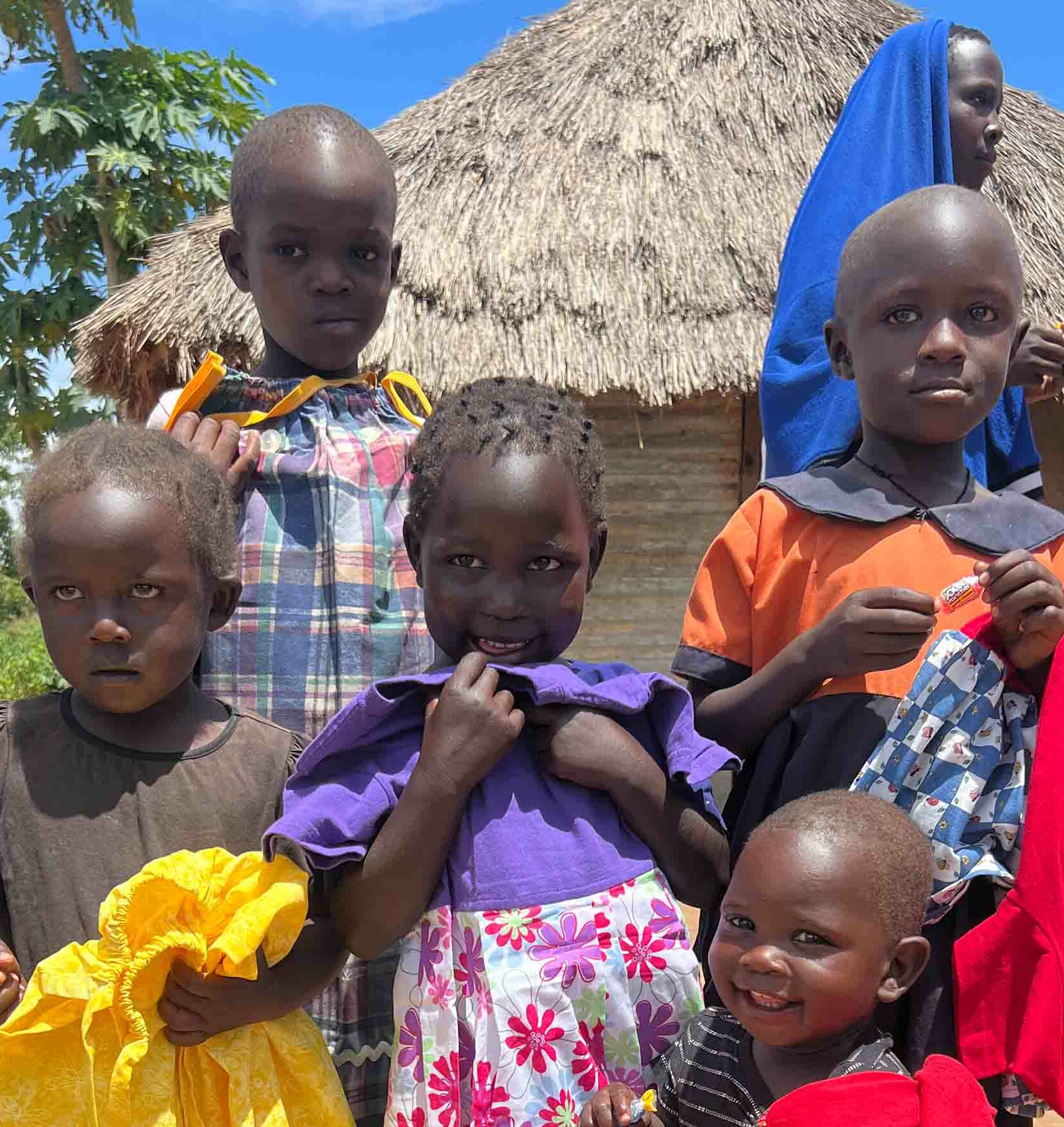 Children in Uganda holding dresses and smiling